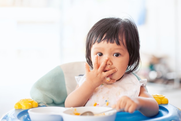 Joli bébé enfant asiatique fille manger des aliments sains par elle-même