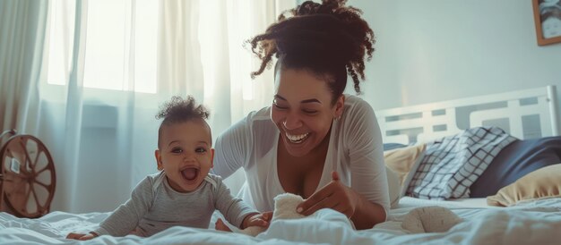 Photo joli bébé fille assise sur sa jeune mère allongée sur le lit souriante à la maison mère avec bébé sur le lit