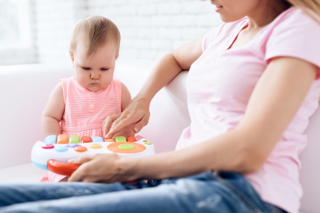 Joli bébé jouant des jouets sur le canapé avec la mère.