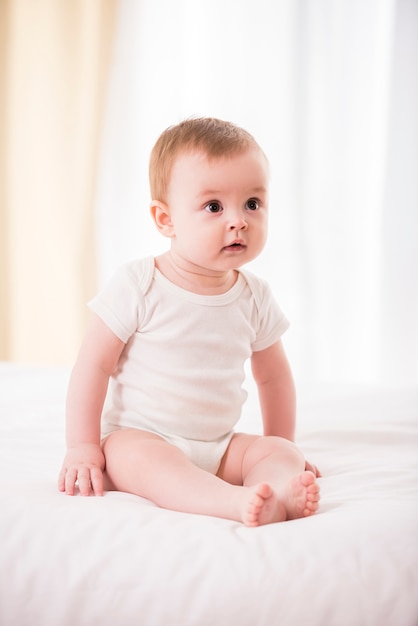 Joli bébé sur le lit dans sa chambre.