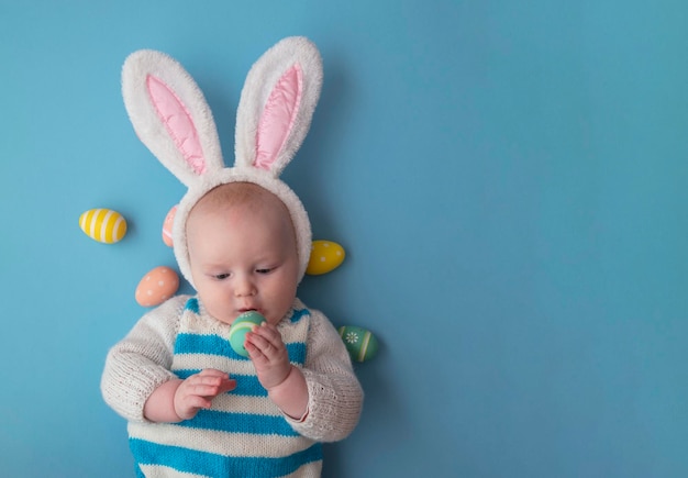 Joli bébé portant des oreilles de lapin de pâques entouré d'oeufs de pâques