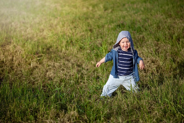 Joli bébé rit, se réjouissant des premiers pas sur l'herbe du parc.