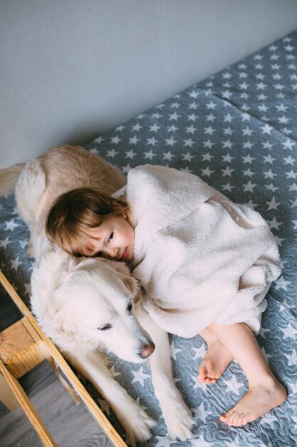 Joli bébé et son labrador retriever à la maison sur le lit