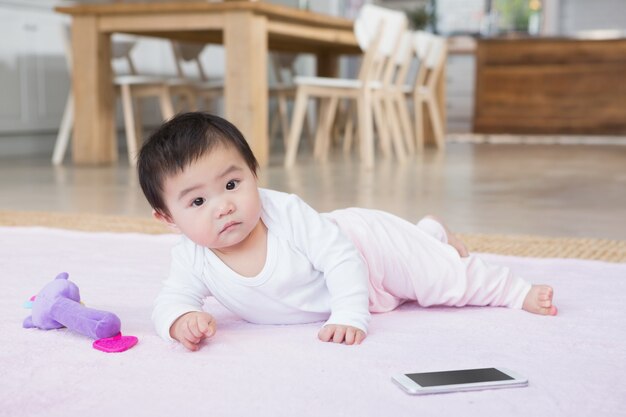 Joli bébé sur le tapis en regardant la caméra