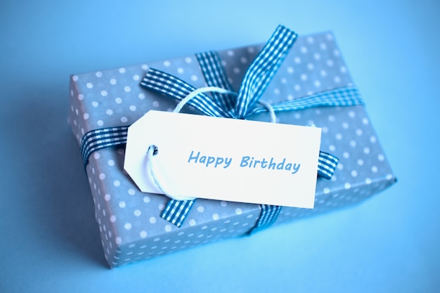 Joli cadeau bleu avec une carte de joyeux anniversaire sur un fond bleu