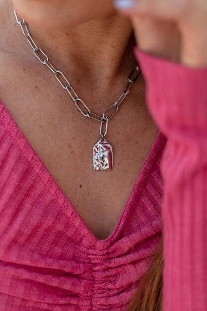 Joli corps frais de femme avec des taches de rousseur dans un haut rose tricoté à la mode avec des bijoux autour du cou en gros plan