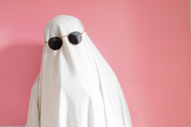 Photo joli costume de fantôme de feuille avec des lunettes de soleil sur un fond rose concept de carnaval de fête d'halloween