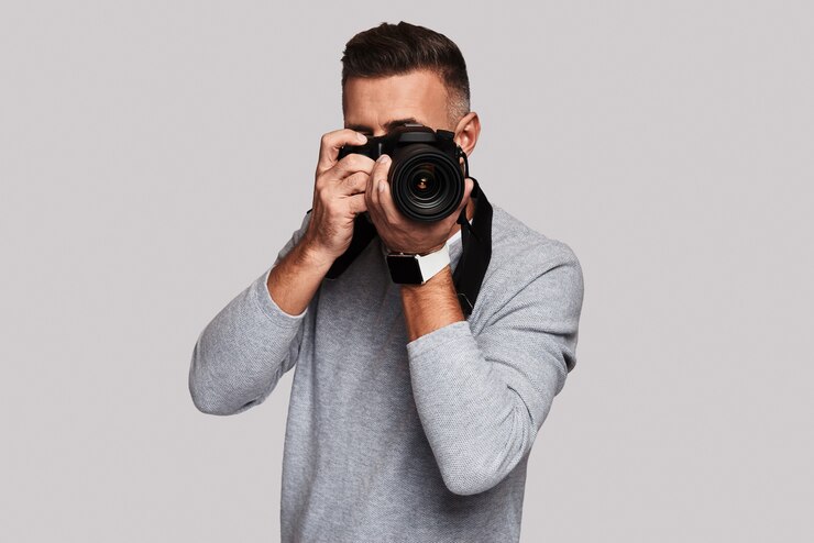 Photo joli coup. beau jeune homme vous photographiant en se tenant debout sur fond gris