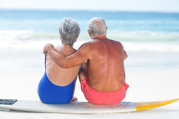 Joli couple d'âge mûr assis sur une planche de surf