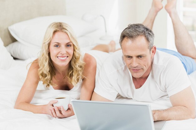 Joli Couple à L'aide D'un Ordinateur Portable Au Lit Dans Leur Chambre