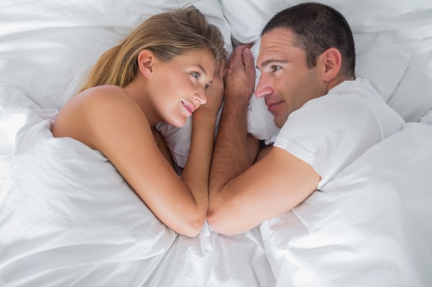 Joli couple allongé et regardant les uns les autres dans son lit