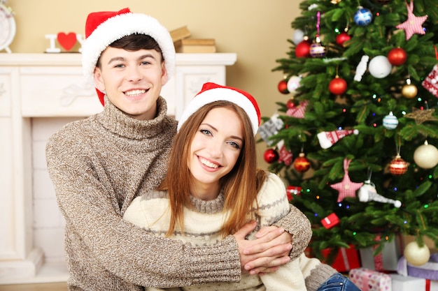 Joli couple amoureux près de l'arbre de Noël. Femme et homme célébrant Noël