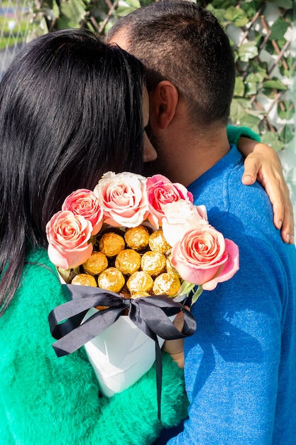 Joli couple amoureux se tenant tout en tenant un bouquet de roses