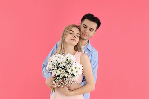 Joli couple avec bouquet sur fond rose