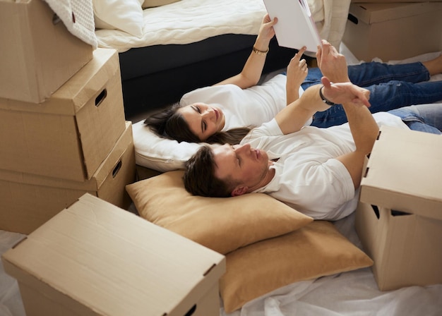 Joli couple déballant des cartons dans leur nouvelle maison gisant sur le sol et regardant un album de famille