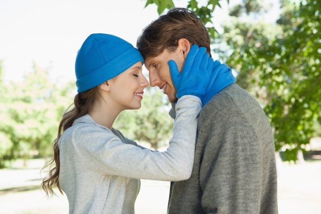 Joli couple debout dans le parc en chapeaux et écharpes