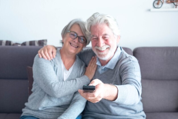 Joli couple de deux personnes âgées matures du Caucase o le canapé regardant un film ou quelque chose à la télévision - homme tenant la télécommande