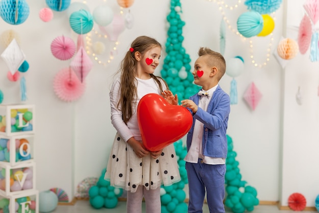 Joli couple d'enfants avec ballon coeur rouge. Concept de la Saint-Valentin et de l'amour, tourné en studio