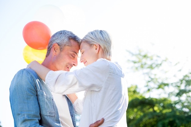 Joli couple étreindre et tenant des ballons au parc