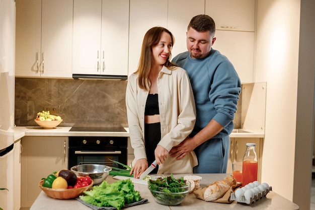 Joli couple familial préparant une salade végétalienne de légumes ensemble dans la cuisine Concept d'alimentation et de régime alimentaire sain Cuisiner à la maison