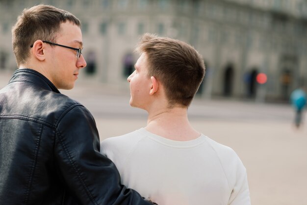 Joli couple gay dans la ville, tendres baisers doux, souriant