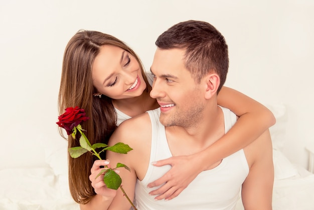 Joli couple heureux en amour embrassant et tenant une rose rouge