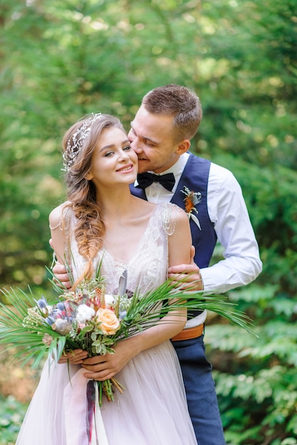 Un joli couple de jeunes mariés, un moment heureux et joyeux. Cermonie de mariage de style bohème dans la forêt au grand air.