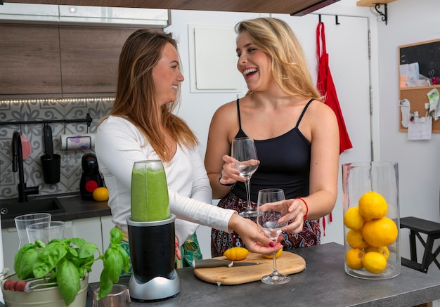 Joli couple de lesbiennes végétaliennes préparant un smoothie aux épinards concept LGTB personnes végétaliennes