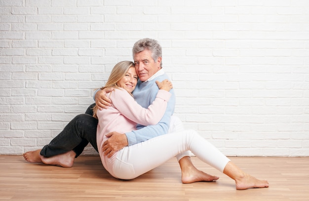 Joli couple de personnes âgées assis sur le sol de leur maison. concept de l&#39;amour