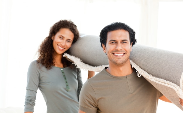 Joli couple portant un tapis debout dans le salon