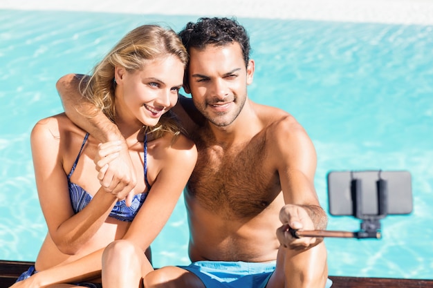 Joli couple prenant selfie au bord de la piscine