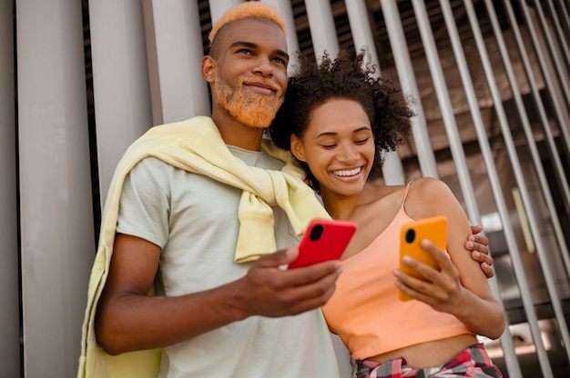 Un joli couple avec des smartphones en mains se sentant bien