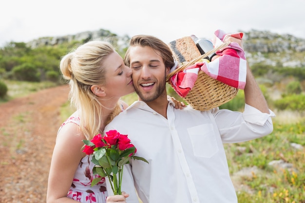 Joli couple va pour un pique-nique avec une femme embrassant la joue de petit ami