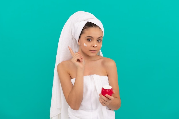 Joli enfant dans la tour de bain appliquant une crème pour le visage beauté adolescente