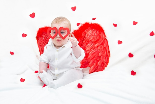 Photo joli enfant mignon avec un style ange cupidon pour la saint-valentin avec des ailes et des lunettes en forme de coeur