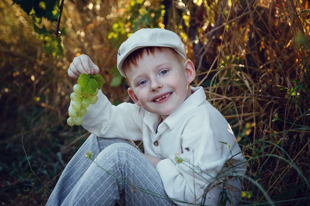 Un joli garçon aux cheveux roux avec des taches de rousseur aide dans le jardin. L'idée et le concept de la scolarisation précoce pour le travail dans le jardin des enfants