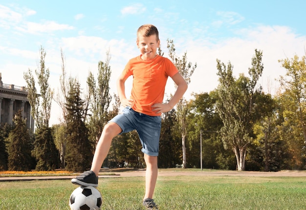 Joli garçon avec ballon de foot sur pelouse