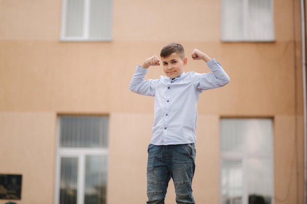 Joli garçon en chemise debout devant l'école