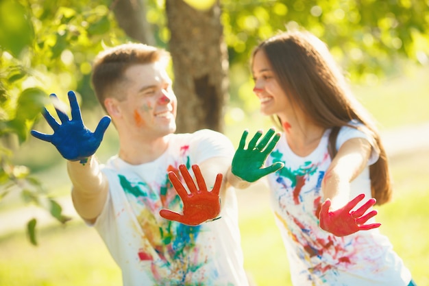 Joli garçon et fille shawing leurs mains peintes ou palmes à la caméra et souriant. Devant la caméra mise au point, il y a un plat multicolore des mains d'un joli couple amoureux.