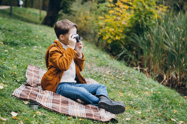 Joli garçon marche et pose dans un parc d'automne coloré