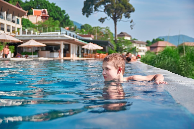 Joli garçon nager dans le fond d'écran de la piscine extérieure Journée chaude et ensoleillée dans les tropiques