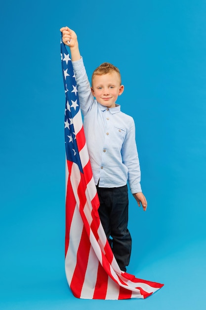 Joli garçon tenant un drapeau américain en studio intérieur sur fond bleu