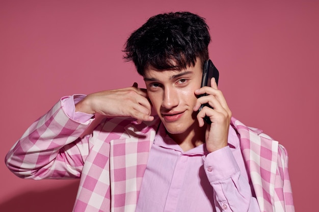Joli homme à la mode parlant au téléphone blazer rose posant un style de vie en studio inchangé
