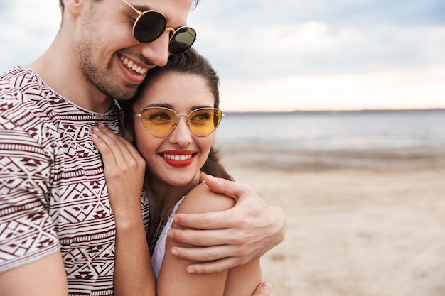 Joli jeune couple passant du temps à la plage, s'embrassant