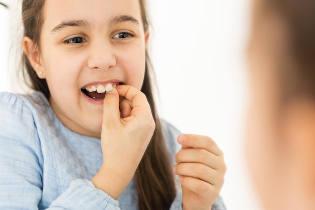 Joli jeune enfant tenant sa dent qui peut être lâche ou douloureuse.