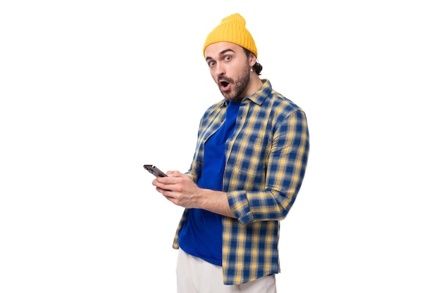 Joli jeune hipster surpris avec un chapeau jaune et une chemise sur fond blanc avec un espace de copie