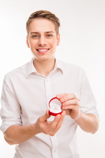 Joli jeune homme tenant une boîte rouge avec bague de mariage et faire une proposition