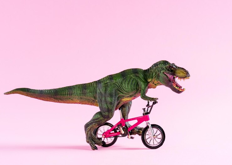 Photo joli jouet de dinosaure heureux, vélo sur fond rose pastel, jolie carte de concept de transport écologique