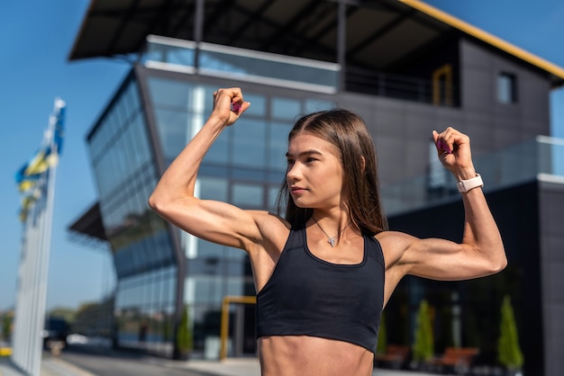 Joli modèle féminin de sport faisant le matin qui s'étend en face du bâtiment en verre moderne, style de vie