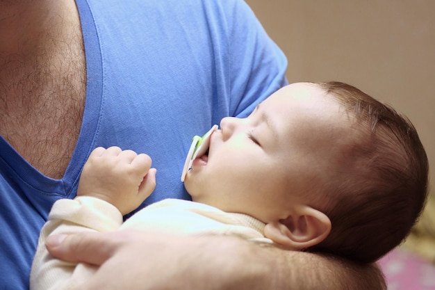 Photo joli nouveau-né dormant dans les bras de son père en gros plan un père aimant porte son nouveau-né à la maison portrait d'une mère heureuse tenant un bébé endormi